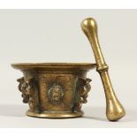 AN EARLY CAST BRONZE PESTLE AND MORTAR ,with mask decoration. 14cms diameter.