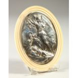 AN IVORY OVAL PLAQUE, the centre inset with a silver plaque depicting an angel and infant. 11cms