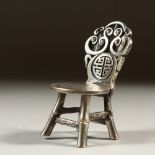 A CHINESE WHITE METAL MINIATURE COIN CHAIR. 7cms high.