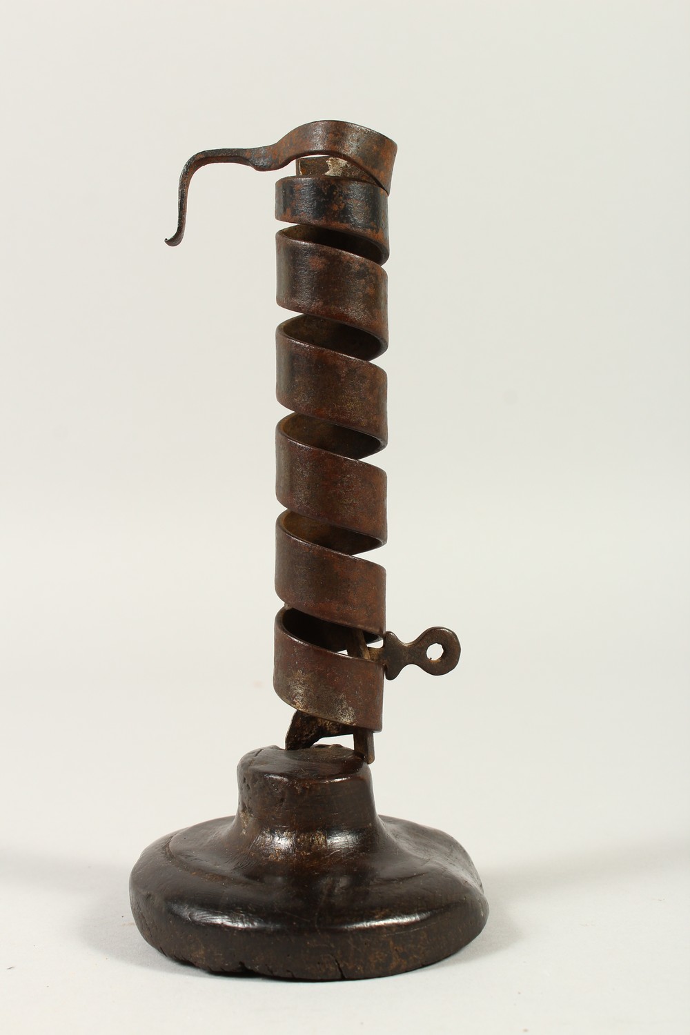 AN EARLY IRON CANDLESTICK, on a wooden base. 19cms high. - Image 2 of 3