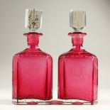 A GOOD PAIR OF RUBY TINTED DECANTERS AND STOPPERS, engraved with flowers. 26cm high.