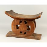 AN AFRICAN HARDWOOD STOOL, with dished top, pierced sides, on a rectangular base. 59cms wide x 40cms