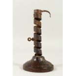 AN EARLY IRON CANDLESTICK, on a wooden base. 19cms high.