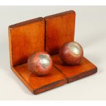 A PAIR OF PRESENTATION SILVER MOUNTED CRICKET BALLS, as bookends. Each 15cms wide.