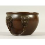 A SMALL CIRCULAR BRONZE CENSER, with mask and ring handles. 11cms diameter.