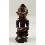 AN OLD TRIBAL FIGURE, a man holding a baby seated on a turtle. 22cms high.