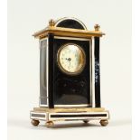 A SMALL FRENCH SILVER AND AGATE CLOCK, with domed top and column supports on bun feet. 8cms high.