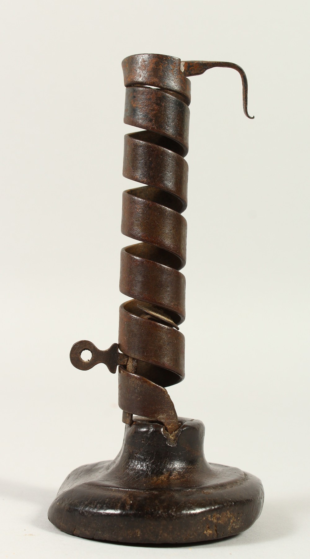 AN EARLY IRON CANDLESTICK, on a wooden base. 19cms high.