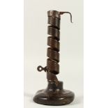 AN EARLY IRON CANDLESTICK, on a wooden base. 19cms high.