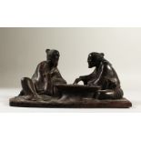 A CARVED WOOD GROUP, two men playing chess. 21cms wide.