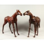 TWO UNUSUAL STUFFED LEATHER MODELS OF STANDING HORSES. 63cms high.