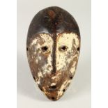 A CARVED TRIBAL MASK, with traces of white pigment decoration. 24cms high.