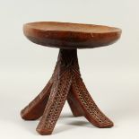 A SMALL AFRICAN HARDOOD STOOL, with circular dished seat, on four curving carved legs. 30cms wide