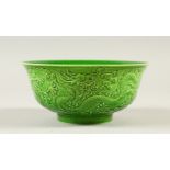 A GREEN GLAZED CIRCULAR BOWL, with moulded dragon decoration. 16cms diameter.