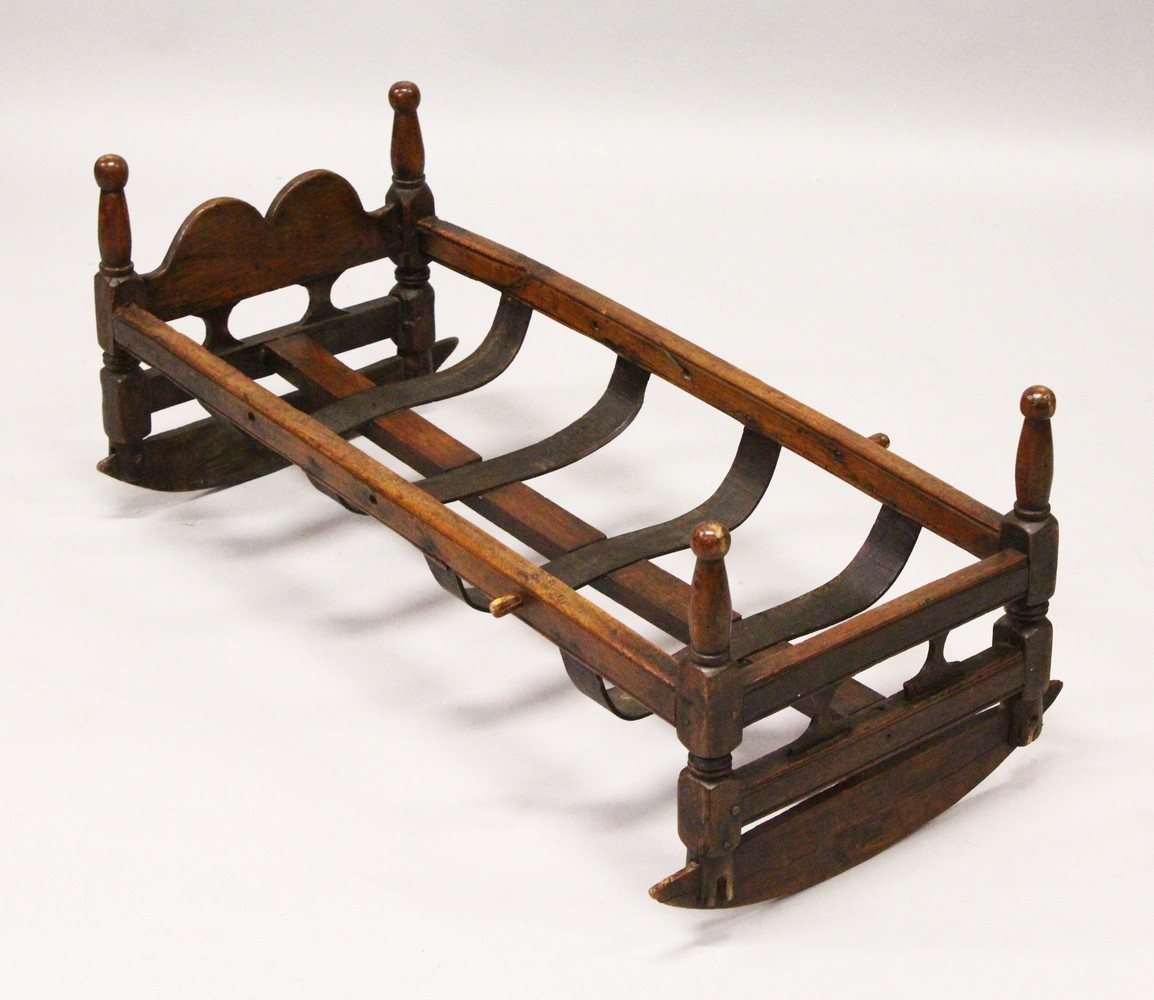 A 19TH CENTURY BEECH CRADLE, with pierced ends, turned corner columns and a slatted base on rockers.