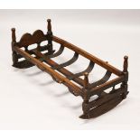 A 19TH CENTURY BEECH CRADLE, with pierced ends, turned corner columns and a slatted base on rockers.