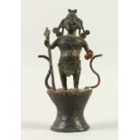 AN EARLY INDIAN METAL GOD, standing on a drum. 24cms high.