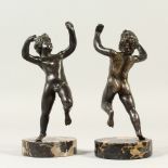 AFTER THE ANTIQUE, A PAIR OF CAST METAL DANCING MALE FIGURES, on circular marble bases. 16cms high.