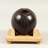 A CARVED COCONUT, signed, on a wood base. Nut: 11cm wide.