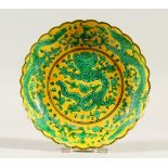 A SMALL SAUCER DISH, yellow ground, decorated in green with dragons. 13.5cms diameter.