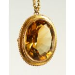 AN OVAL CITRINE PENDANT on a gold chain.