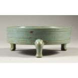 A TURQUOISE GLAZED CIRCULAR BRUSHWASHER, on three curving feet. 16cms diameter.