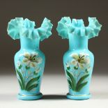 A PAIR OF PALE BLUE GLASS VASES, painted with flowers. 17cm high.