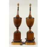 A PAIR OF REGENCY STYLE PAINTED POTTERY URN SHAPED TABLE LAMPS, on shaped square bases. 65cms high.