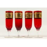 A SET OF FOUR RED AND GOLD GLASSES.
