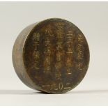 A CIRCULAR BRONZE BOX AND COVER, engraved with calligraphy. 7.5cms diameter.
