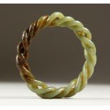 A GREEN JADE TWISTED BANGLE. 8cms diameter.