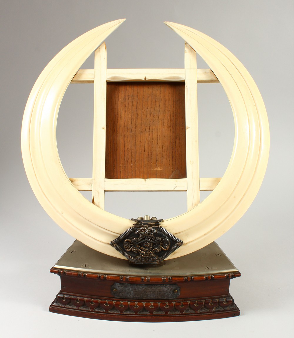 A LATE 19TH CENTURY BOARS TUSK PHOTOGRAPH FRAME, the pair of tusks joined by an ornate clasp,