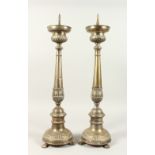 A PAIR OF METAL PRICKET CANDLESTICKS, on circular bases with claw feet. 66cms high.
