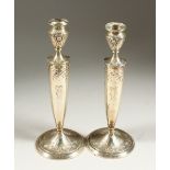 A PAIR OF SILVER ENGRAVED CIRCULAR CANDLESTICKS. 25cms high.