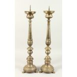 A PAIR OF METAL PRICKET CANDLESTICKS, on circular bases with claw feet. 75cms high.