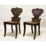 A GOOD PAIR OF REGENCY MAHOGANY HALL CHAIRS, with shaped backs, solid seats, on curving legs.