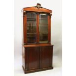 A LATE REGENCY MAHOGANY BOOKCASE, the top with double panel glass doors enclosing three shelves,