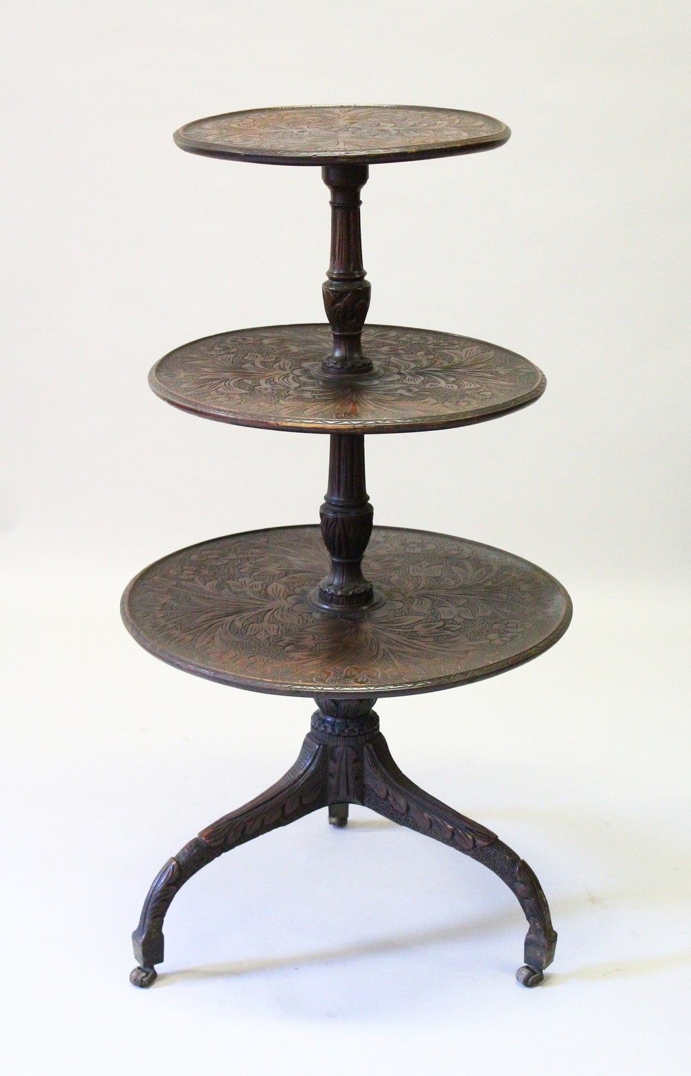 A GEORGE III MAHOGANY CARVED THREE TIER DUMB WAITER with centre column support ending in tripod