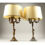 A PAIR OF FRENCH GILDED METAL THREE-LIGHT CANDELABRA, with scrolling branches and cupid bases. 52cms