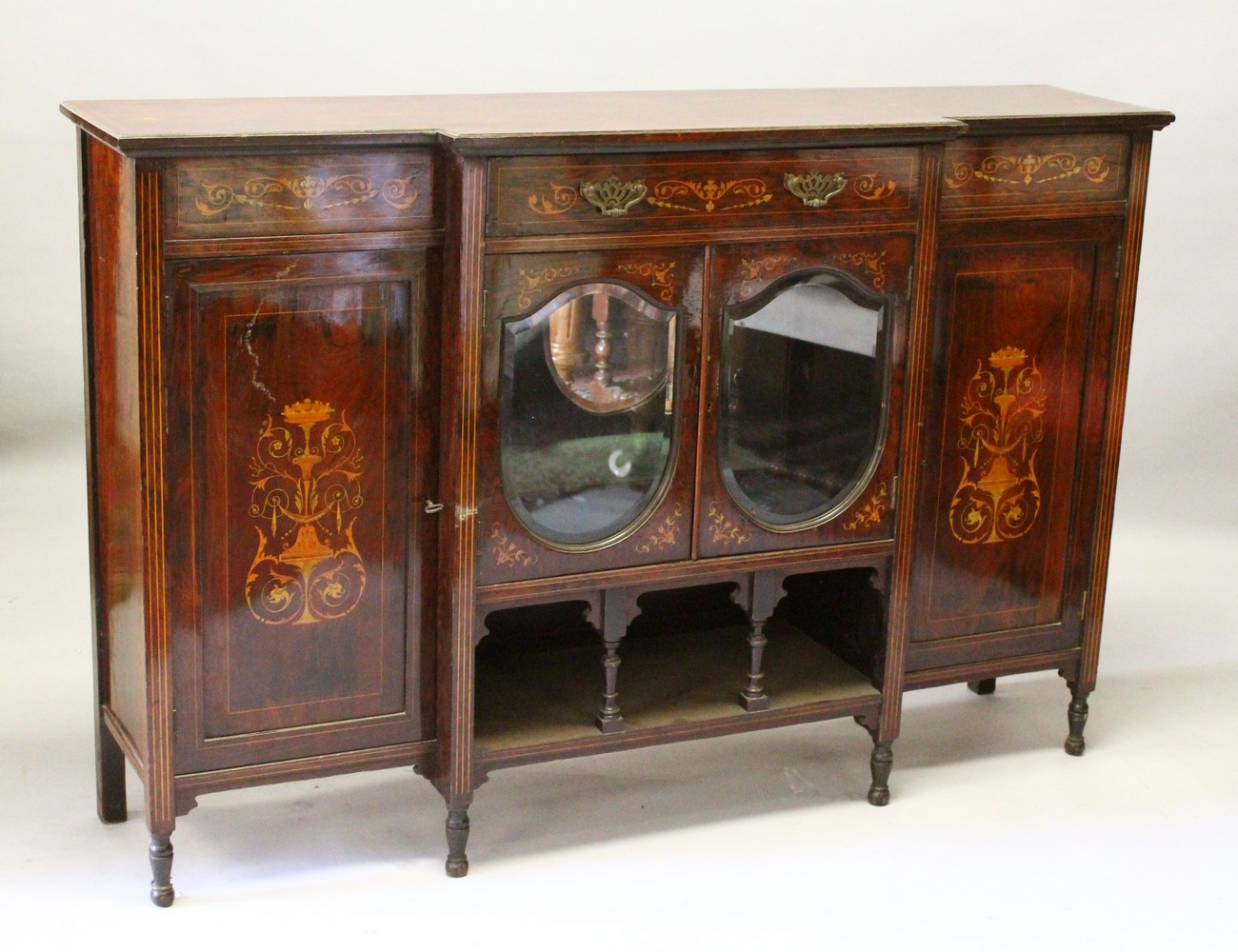 AN EDWARDIAN ROSEWOOD INLAID BREAKFRONT CUPBOARD, the centre with two oval mirrored doors with shelf
