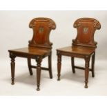 A GOOD PAIR OF REGENCY MAHOGANY HALL CHAIRS, with shaped backs with armorial's, solid seats, on