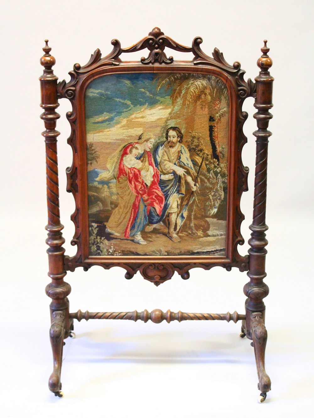 A VICTORIAN MAHOGANY FIRE SCREEN with Berlin tapestry, on curving legs. 116cms high x 74cms wide.