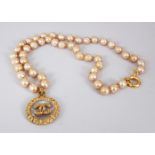 A CHANEL PEARL NECKLACE, with gilt metal and glass double-sided logo pendant.