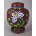 AN EARLY 20TH CENTURY CHINESE RED GROUND CLOISONNE JAR & COVER, together with a fitted wood stand,