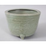 A MING CELADON CIRCULAR PLANTER, with etched sides, on three short legs. 13cms diameter.