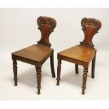 A GOOD PAIR OF REGENCY MAHOGANY HALL CHAIRS, with shaped backs, solid seats, on turned legs.