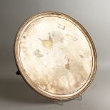 A LARGE CIRCULAR SALVER, with reeded border, the centre engraved with initials, on three curving