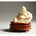 A VERY GOOD CARVED IVORY LAUGHING SEATED BUDDHA. 9cms long x 8cms high, on a carved wooden stand.