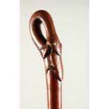 A WOODEN WALKING STICK, the handle as a snake eating a frog. 87cms long.