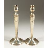 A PAIR OF SILVER ENGRAVED CIRCULAR CANDLESTICKS, with octagonal stems. 25cms high.